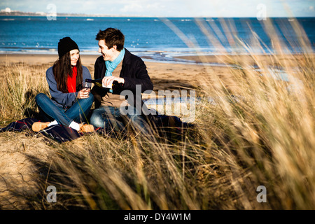 Couples célébrant avec le vin blanc sur la plage, Bournemouth, Dorset, UK Banque D'Images