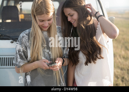 Deux jeunes femmes à l'écoute de la musique sur un lecteur mp3 Banque D'Images