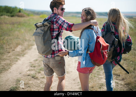 Trois amis marchant sur un chemin de terre avec des sacs à dos Banque D'Images