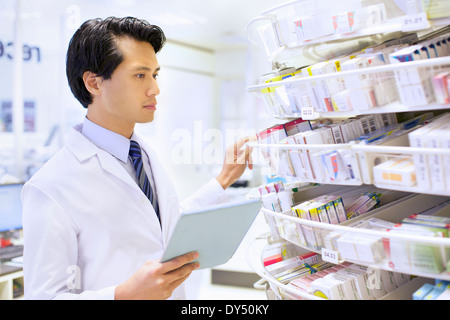 Homme pharmacien la prise de stock en pharmacie Banque D'Images