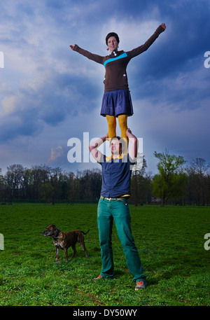 Jeune femme debout sur les épaules de l'homme dans le parc acrobatique, acrobat. Banque D'Images