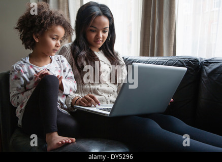 Deux sisters sitting on sofa using laptop Banque D'Images