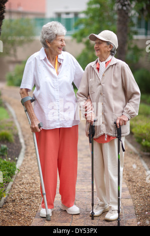 Deux femmes âgées se promener à la retraite villa garden Banque D'Images