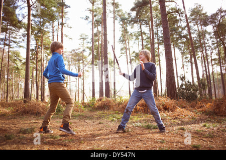 Les frères jumeaux jouer avec des bâtons de combat en forêt Banque D'Images