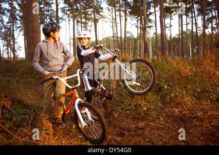 Les frères jumeaux holding vélos BMX chatting in forest Banque D'Images