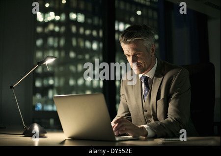 Businessman working on laptop in office tardif Banque D'Images