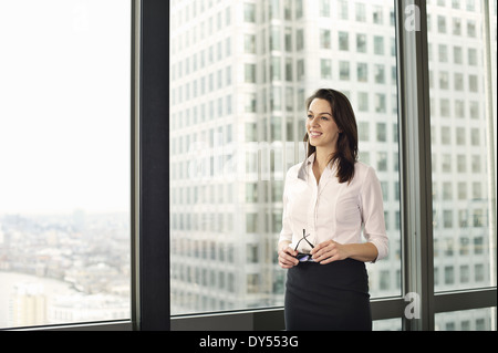 Portrait of young businesswoman looking out of office window Banque D'Images