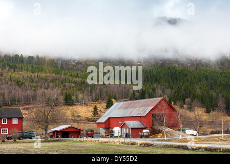 Paysage norvégien rurale avec des maisons en bois rouge et les nuages sur les collines Banque D'Images