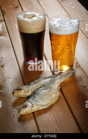 Deux verres de bière avec du poisson séché sur une table Banque D'Images