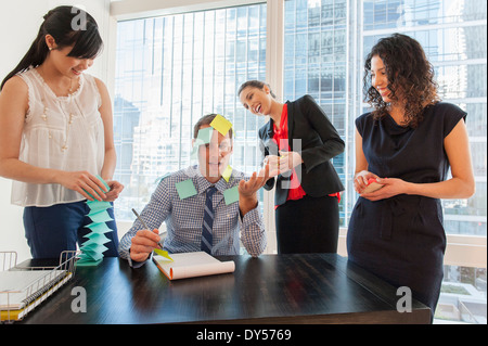 Les travailleurs de bureau couvrant collègue masculin avec sticky notes Banque D'Images