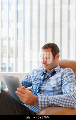Mid adult man relaxing at home with digital tablet Banque D'Images