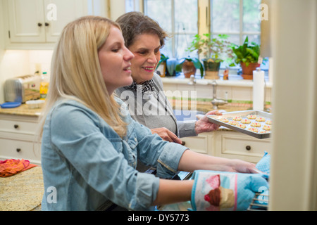 Senior woman and granddaughter baking biscuits au four Banque D'Images