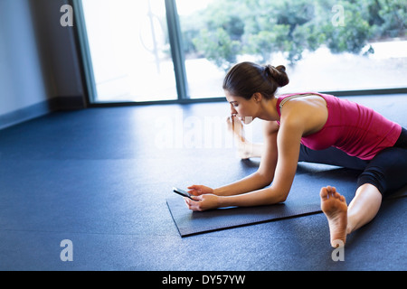 Jeune femme dans la posture yoga using cellular phone Banque D'Images