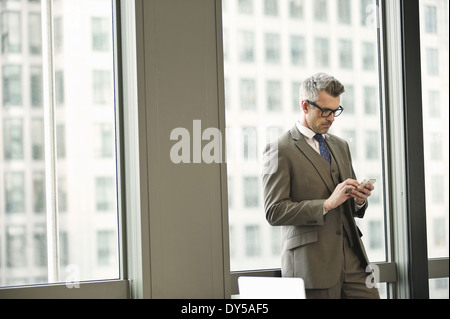 Businessman texting on smartphone in office Banque D'Images