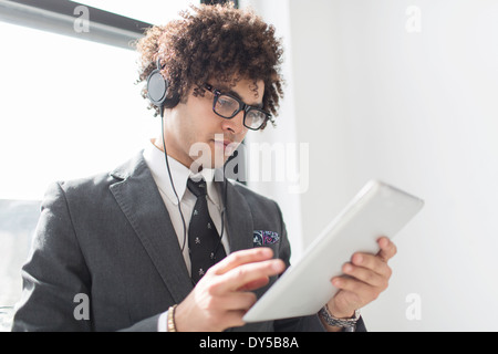 Young man wearing headphones using digital tablet Banque D'Images