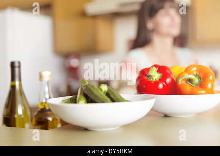 Mid adult woman in kitchen avec bols de légumes sur le comptoir Banque D'Images