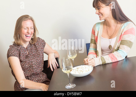 Mid adult female friends drinking white wine and laughing Banque D'Images