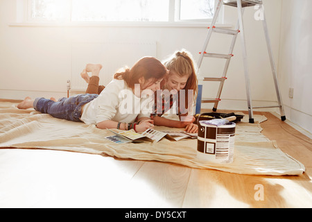 Deux sœurs adolescentes lying on floor looking at color swatches Banque D'Images