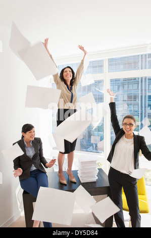 Trois jeunes businesswoman throwing papers mid air Banque D'Images