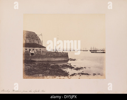La vue sur le port de Bombay depuis l'Apollo Pier capture le front de mer animé avec des voiliers, des quais et des jetées. Il met en lumière les activités maritimes animées de l’un des principaux ports de l’Inde au début du XXe siècle. Banque D'Images