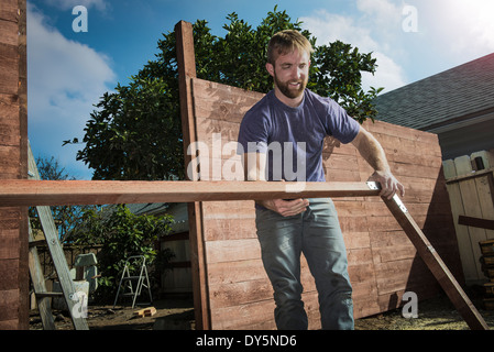 Joiner in backyard lifting cadre bois Banque D'Images