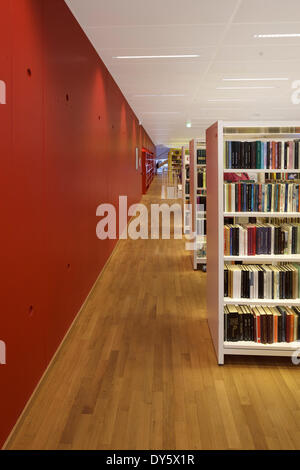 Bibliothèque de Molde (Norvège Molde Molde bibliotek). Architecte : 3XN 2012. Étagères blanches avec mur rouge au premier étage. Banque D'Images