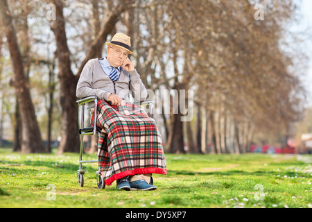 Grumpy Old homme assis dans un fauteuil roulant à l'extérieur Banque D'Images