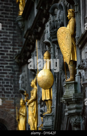 BRUGES, Belgique — des statues dorées ornent l'extérieur de la Basilique du Saint-sang, une église médiévale sur la place Burg. La structure gothique ornée, célèbre pour abriter une relique du sang du Christ, présente une décoration architecturale élaborée comprenant ces figures dorées. Ces éléments sculpturaux témoignent des riches traditions artistiques de l'architecture religieuse médiévale. Banque D'Images