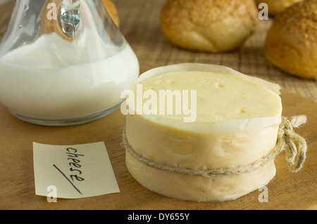 Bouteille de lait et fromage de tête sur une table en bois avec un autocollant du fromage. Pain d'arrière-plan. Banque D'Images