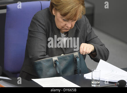 Berlin, Allemagne. Le 08 Avr, 2014. La chancelière allemande, Angela Merkel (CDU) cherche quelque chose dans son sac à main pendant le débat sur le budget fédéral pour l'année 2014 au Bundestag à Berlin, Allemagne, le 08 avril 2014. Photo : TIM BRAKEMEIER/DPA/Alamy Live News Banque D'Images