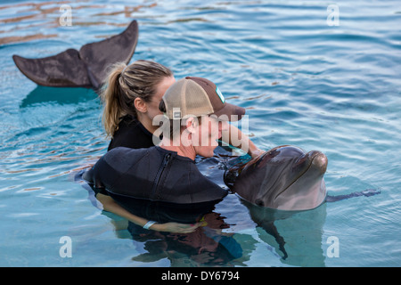 Un formateur montre une femme comment toucher un dauphin à l'Atlantis Resort & Casino Dolphin Cay Paradise Island Nassau, Bahamas. Banque D'Images