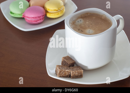 Machine à café expresso en blanc tasse sur table en bois avec un bol de macarons colorés Banque D'Images