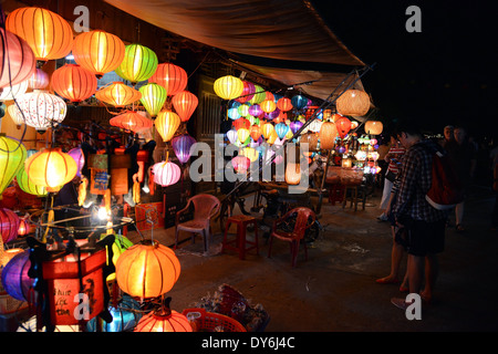 Les touristes et la population locale shopping de nuit à un stand vendant des lanternes en papier pour la Fête des lanternes, Hoi An, Vietnam Banque D'Images