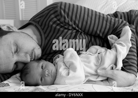 Image en noir et blanc du père allongé avec sa petite fille de nouveau-né câlin Banque D'Images