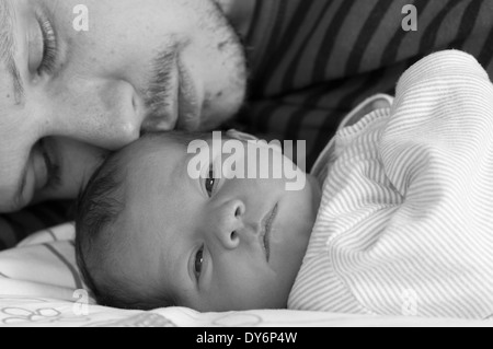 Image courte en noir et blanc du père allongé avec sa petite fille de nouveau-né câlin Banque D'Images