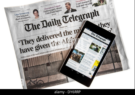 Tablette numérique à écran tactile en ligne montrant les nouvelles du monde sur le dessus de la Le Daily Telegraph sur fond blanc Banque D'Images