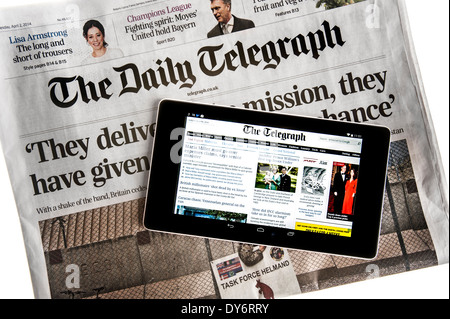 Tablette numérique à écran tactile en ligne montrant les nouvelles du monde sur le dessus de la Le Daily Telegraph sur fond blanc Banque D'Images