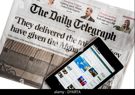 Tablette numérique à écran tactile en ligne montrant les nouvelles du monde sur le dessus de la Le Daily Telegraph sur fond blanc Banque D'Images