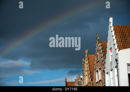 BRUGES, Belgique — Un arc-en-ciel vole au-dessus du paysage urbain médiéval de Bruges, contrastant de façon spectaculaire avec les nuages sombres de tempête. Le phénomène naturel encadre l'architecture historique de la ville classée au patrimoine mondial de l'UNESCO. Cette scène atmosphérique met en valeur le caractère médiéval préservé de l'horizon de Bruges. Banque D'Images