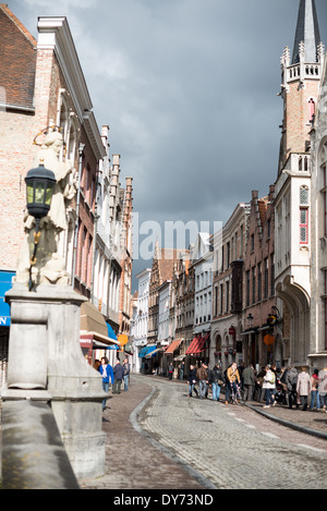 BRUGES, Belgique — Wollestraat, principale artère médiévale menant de la place Markt centrale de Bruges, conserve son caractère historique et sa tradition commerciale. Cette rue vitale illustre l'urbanisme médiéval préservé du centre-ville de Bruges. L'architecture historique et le tracé des rues démontrent la continuité de la vie urbaine de l'époque médiévale à nos jours. Banque D'Images