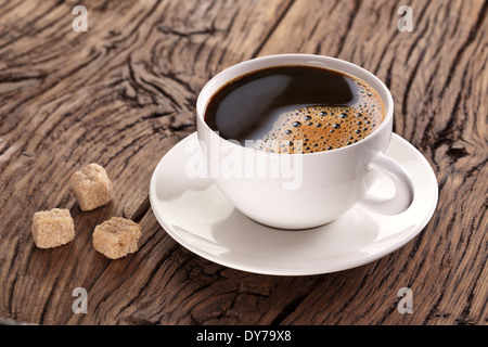 Tasse de café et des morceaux de sucre brun près d'elle sur la vieille table en bois. Banque D'Images