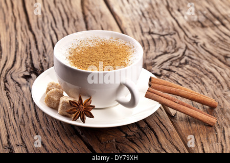 Tasse de cappuccino décoré avec des épices et des cubes de sucre brun près de lui. Banque D'Images