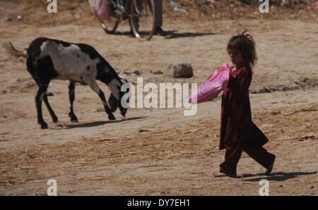 Islamabad, Pakistan. 8 avril, 2014. Un réfugié afghan girl passe devant une chèvre dans le bidonville d'Islamabad le 8 avril 2014. Selon l'Organisation des Nations Unies pour les réfugiés, le HCR, il y a environ 2,6 millions d'Afghans au Pakistan, dont la plupart vivent ici depuis le début des années 1980 lorsque l'ancien Union soviétique a envahi leur pays. Avec peu d'occasions de faire leur vie au Pakistan, ils veulent retourner chez eux mais seulement après la paix est rétablie en Afghanistan. Credit : PACIFIC PRESS/Alamy Live News Banque D'Images