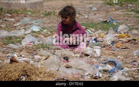 Islamabad, Pakistan. 8 avril, 2014. Un réfugié afghan girl est assis sur une poubelle pour trouver quelques trucs comestibles dans le bidonville d'Islamabad le 8 avril 2014. Selon l'Organisation des Nations Unies pour les réfugiés, le HCR, il y a environ 2,6 millions d'Afghans au Pakistan, dont la plupart vivent ici depuis le début des années 1980 lorsque l'ancien Union soviétique a envahi leur pays. Avec peu d'occasions de faire leur vie au Pakistan, ils veulent retourner chez eux mais seulement après la paix est rétablie en Afghanistan. Credit : PACIFIC PRESS/Alamy Live News Banque D'Images