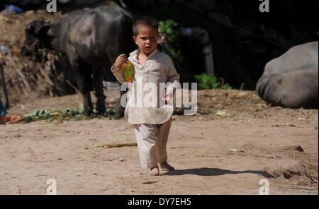 Islamabad, Pakistan. 8 avril, 2014. Un réfugié afghan enfant marche dans sa maison de terre dans le bidonville d'Islamabad le 8 avril 2014. Selon l'Organisation des Nations Unies pour les réfugiés, le HCR, il y a environ 2,6 millions d'Afghans au Pakistan, dont la plupart vivent ici depuis le début des années 1980 lorsque l'ancien Union soviétique a envahi leur pays. Avec peu d'occasions de faire leur vie au Pakistan, ils veulent retourner chez eux mais seulement après la paix est rétablie en Afghanistan. Credit : PACIFIC PRESS/Alamy Live News Banque D'Images