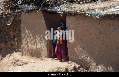 Islamabad, Pakistan. 8 avril, 2014. Enfants réfugiés afghans se tiennent à la porte de leur maison de terre dans le bidonville d'Islamabad le 8 avril 2014. Selon l'Organisation des Nations Unies pour les réfugiés, le HCR, il y a environ 2,6 millions d'Afghans au Pakistan, dont la plupart vivent ici depuis le début des années 1980 lorsque l'ancien Union soviétique a envahi leur pays. Avec peu d'occasions de faire leur vie au Pakistan, ils veulent retourner chez eux mais seulement après la paix est rétablie en Afghanistan. Credit : PACIFIC PRESS/Alamy Live News Banque D'Images