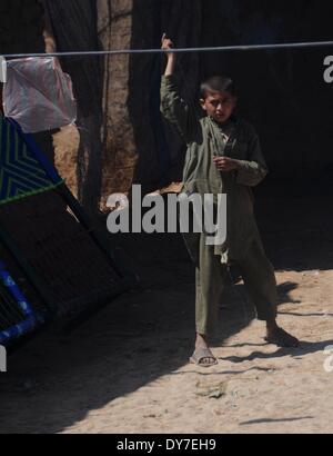 Islamabad, Pakistan. 8 avril, 2014. Un réfugié afghan garçon joue devant sa maison de terre dans le bidonville d'Islamabad le 8 avril 2014. Selon l'Organisation des Nations Unies pour les réfugiés, le HCR, il y a environ 2,6 millions d'Afghans au Pakistan, dont la plupart vivent ici depuis le début des années 1980 lorsque l'ancien Union soviétique a envahi leur pays. Avec peu d'occasions de faire leur vie au Pakistan, ils veulent retourner chez eux mais seulement après la paix est rétablie en Afghanistan. Credit : PACIFIC PRESS/Alamy Live News Banque D'Images