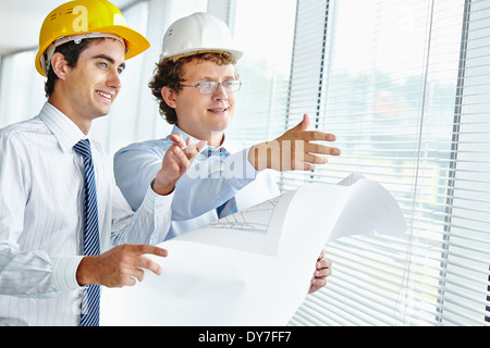 Les architectes à la fenêtre au moyen d'hommes en discutant de croquis de nouvelle construction Banque D'Images