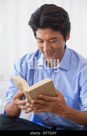 Happy man sitting on couch reading Banque D'Images