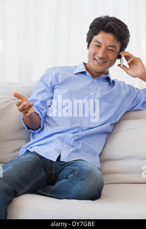 Heureux homme assis sur la table sur le téléphone Banque D'Images